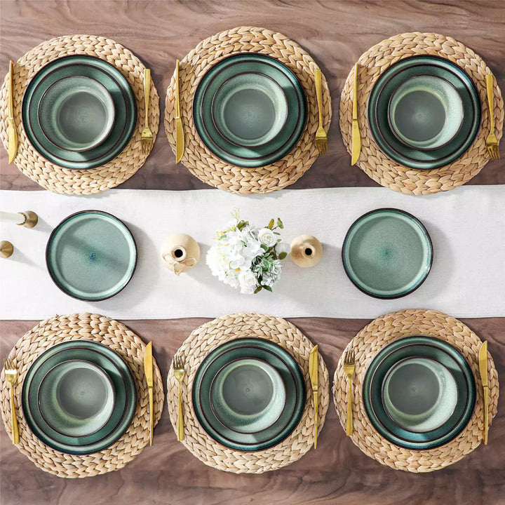 Sata green stoneware 24 piece dinnerware set styled on wood table with white runner candles and flowers farmhouse reactive glaze service for 6.