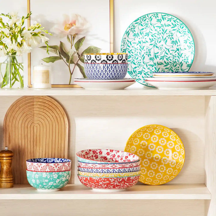 Selene vibrant porcelain pasta bowls set of 6 colorful ceramic dinnerware stacked in white wooden cabinet with fresh flowers and candles.