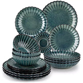 Adonis 16 piece reactive glaze dinnerware set in teal green with pasta steak and fruit on a wooden dining table