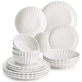 Adonis 16 piece white porcelain dinnerware set with steak pasta and fruit on a wooden dining table