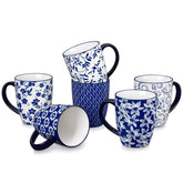 Set of six Japanese-style stoneware mugs in blue and white with indigo patterns, displayed on a kitchen counter with scattered coffee beans