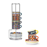 Simi 12 piece porcelain espresso set with 3oz cups and saucers in vibrant boho chic floral patterns on a black metal storage rack with a magazine and napkin on a wooden table