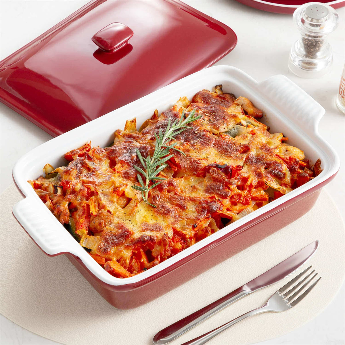3.8Qt stoneware casserole with roasted food and bay leaf garnish on white table with pepper shaker.