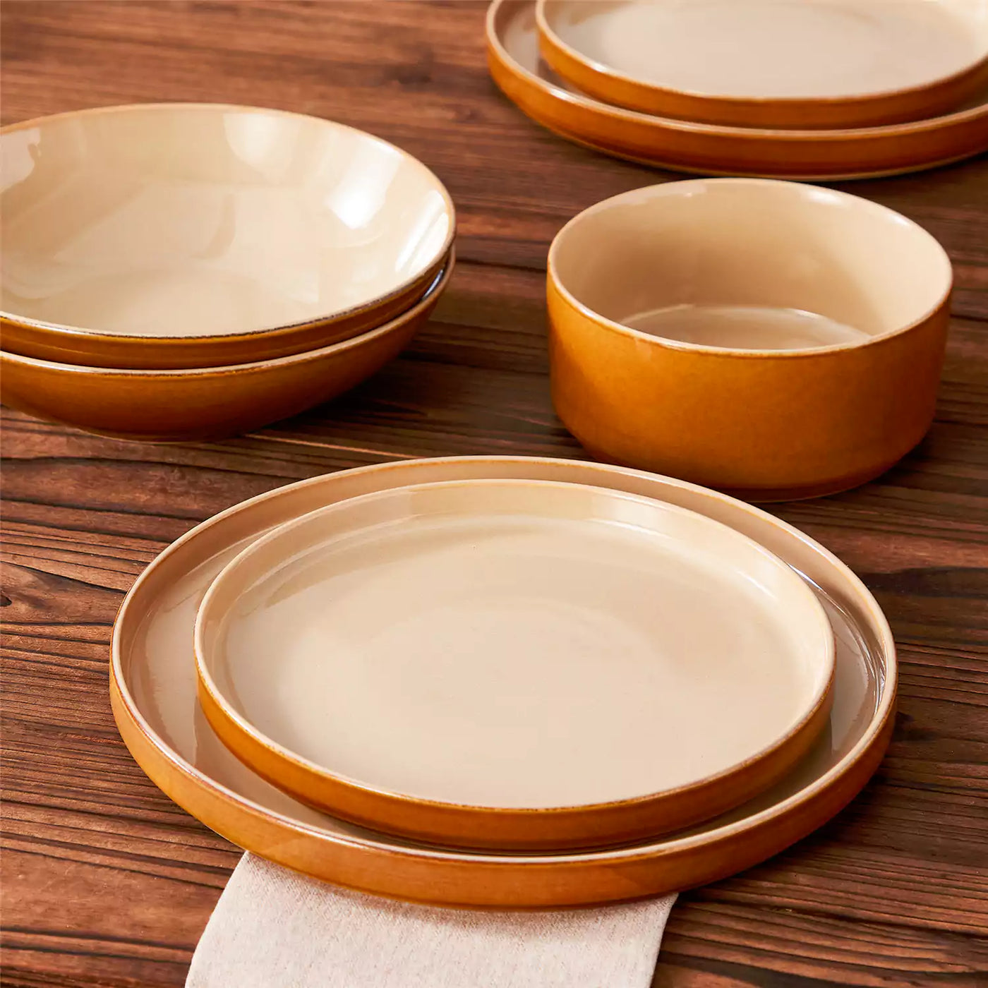 Onion 16-piece reactive glaze dinnerware set displayed on a dark wood table with neutral tones, styled with cream napkins.