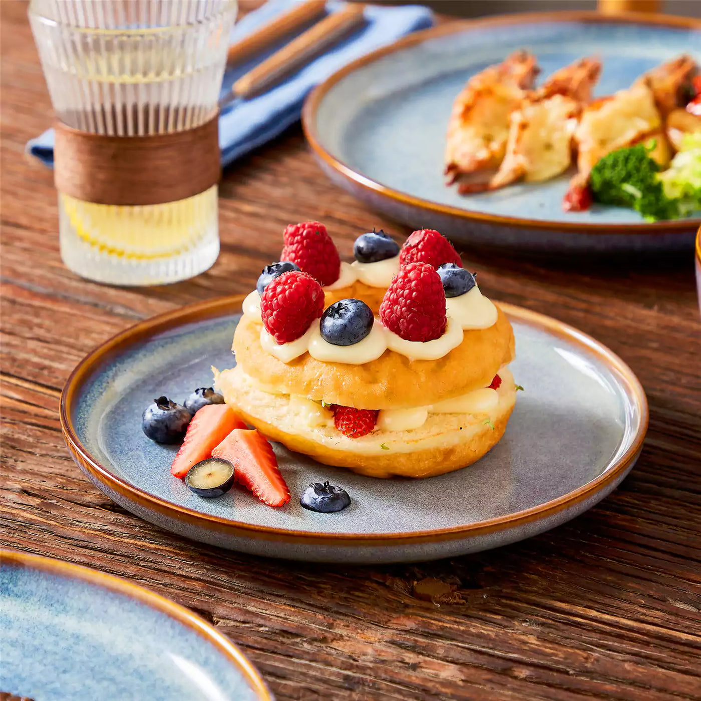 Deep indigo dessert plate with soufflé cake on a wooden table, Playa dinnerware set with cheesy baked shrimp.