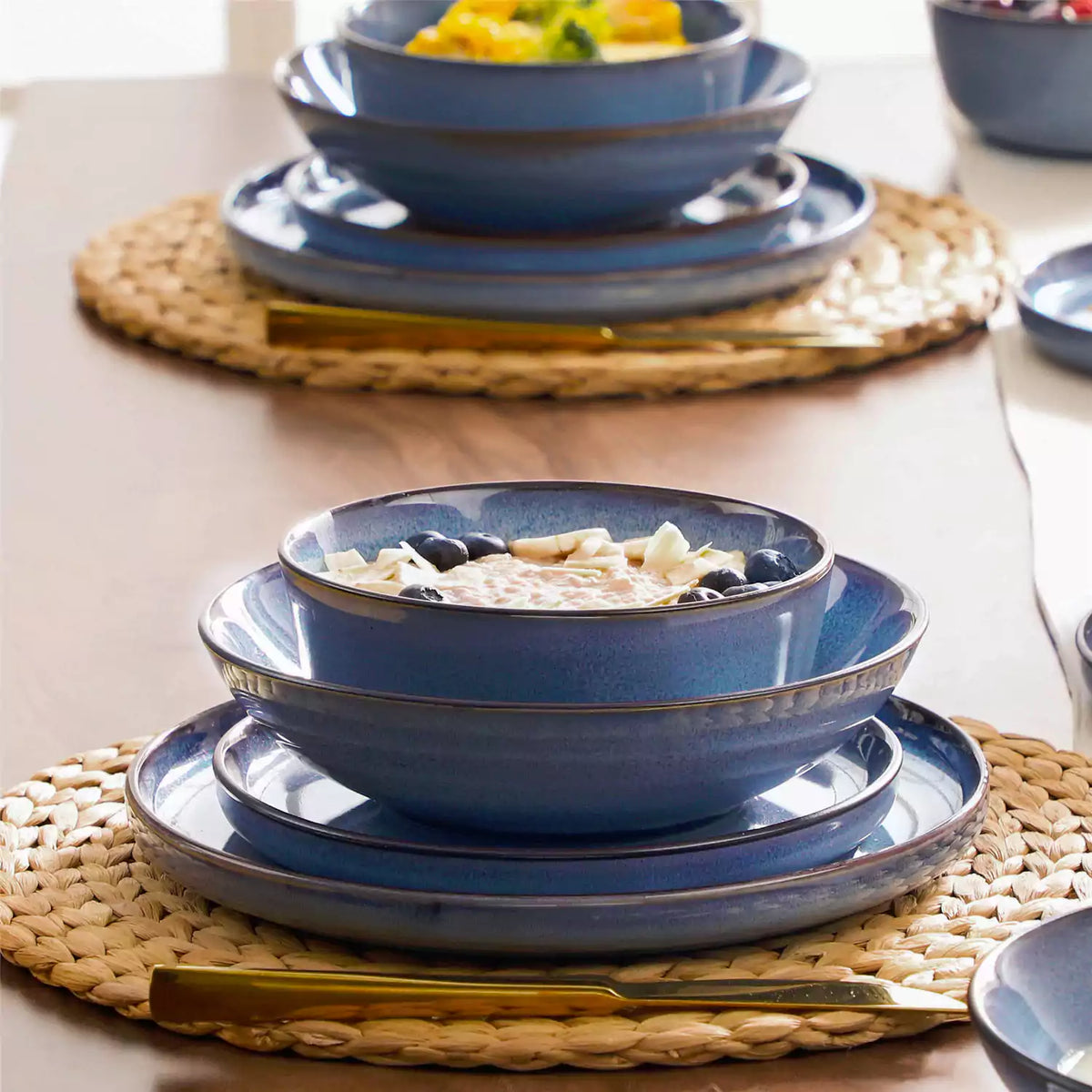Sata blue reactive glaze stoneware dinnerware stacked plates and oatmeal bowl with berries wood table gold flatware.