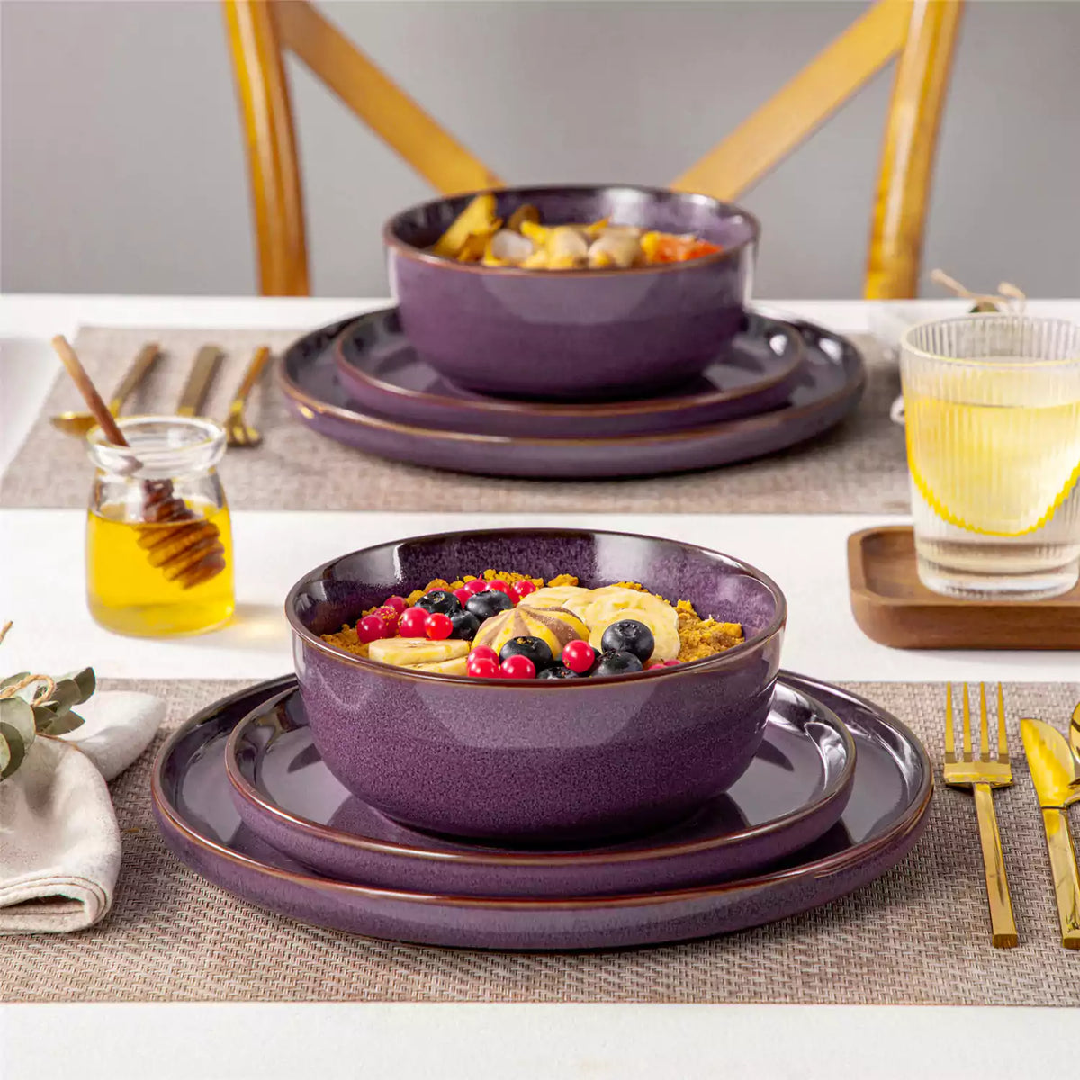 Sata 12-piece purple dinnerware set with dinner plate, dessert plate, and cereal bowl stacked with berry banana oatmeal.