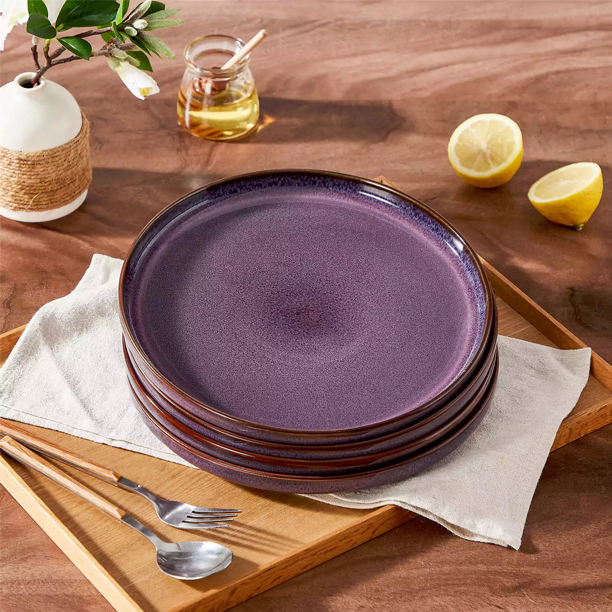 Sata purple stoneware dinner plates set of 4 stacked featuring farmhouse reactive glaze finish styled on wood dining table with lemon and white floral vase.