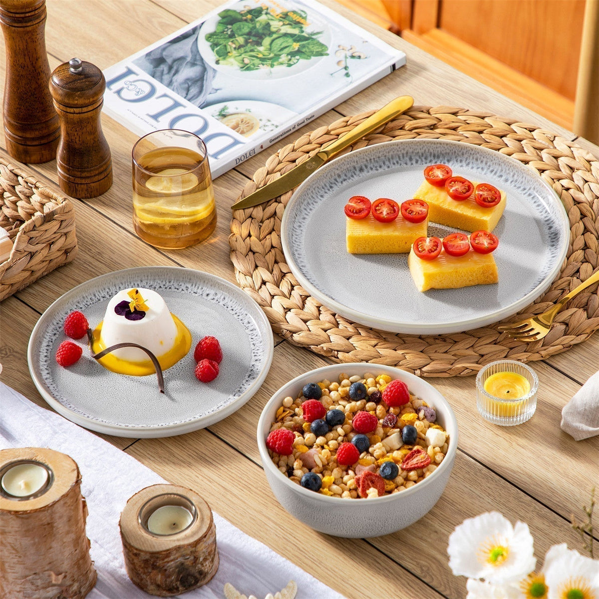 Snow 18-piece dinnerware set with beige reactive glaze, cakes and oats on woven placemat with wooden candle