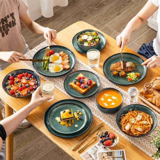 Starry Lipped-Edge 24-piece dinnerware set in green, with pasta, pumpkin soup, and berry salad, artfully arranged on a wooden table with a lace table runner.