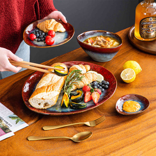 Starry 11 piece stoneware dinnerware set red reactive glaze plates serving berries bread on wood table with lemon garnish.