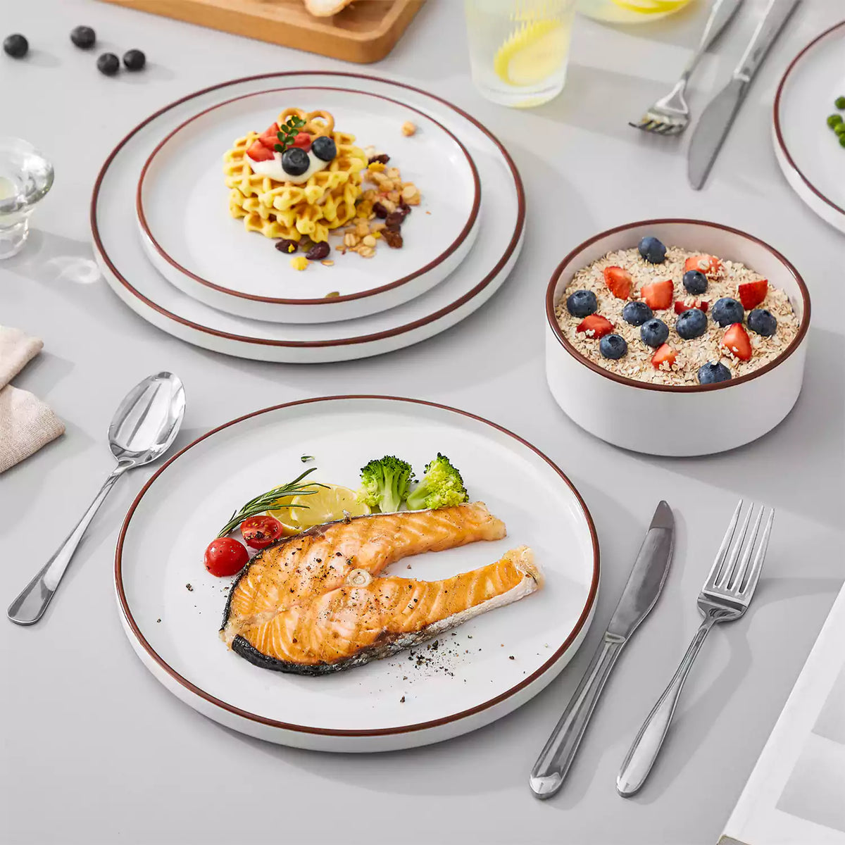 Venus glossy white stoneware with brown trim holding grilled salmon and fresh fruit salad.
