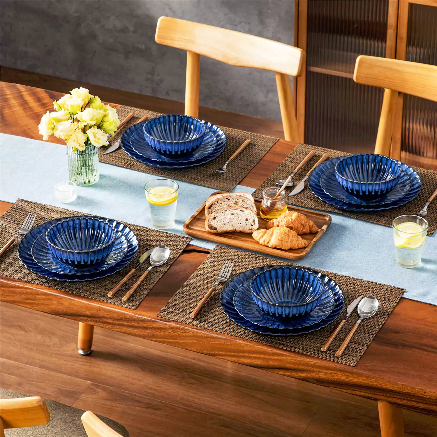 Blue reactive glaze stoneware bowls and plates from the Adonis 12 piece set with brown placemats and fresh flowers