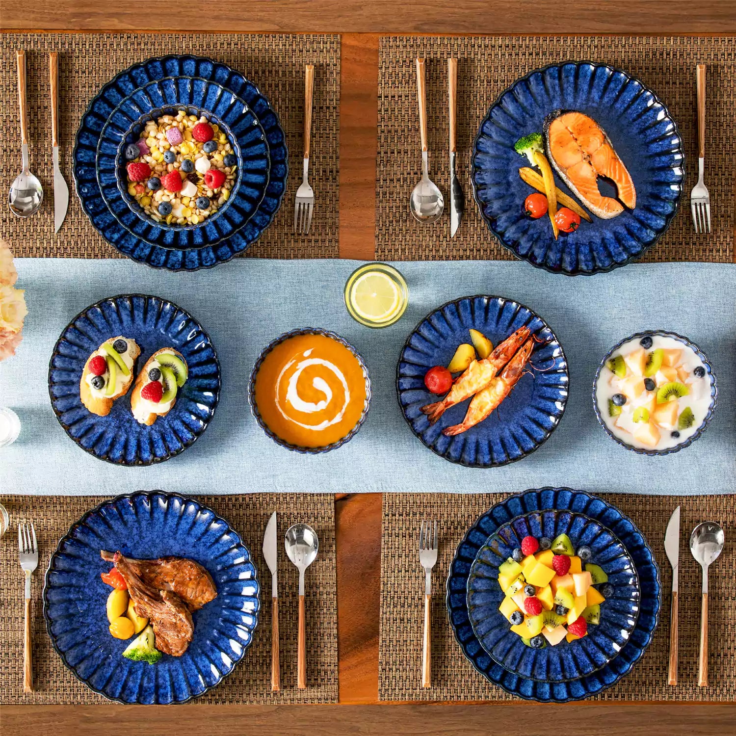 Blue reactive glaze stoneware bowls and plates from the Adonis 12 piece set with brown placemats and fresh flowers