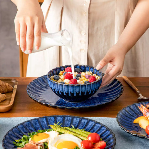 Blue reactive glaze stoneware bowls and plates from the Adonis 12 piece set with brown placemats and fresh flowers