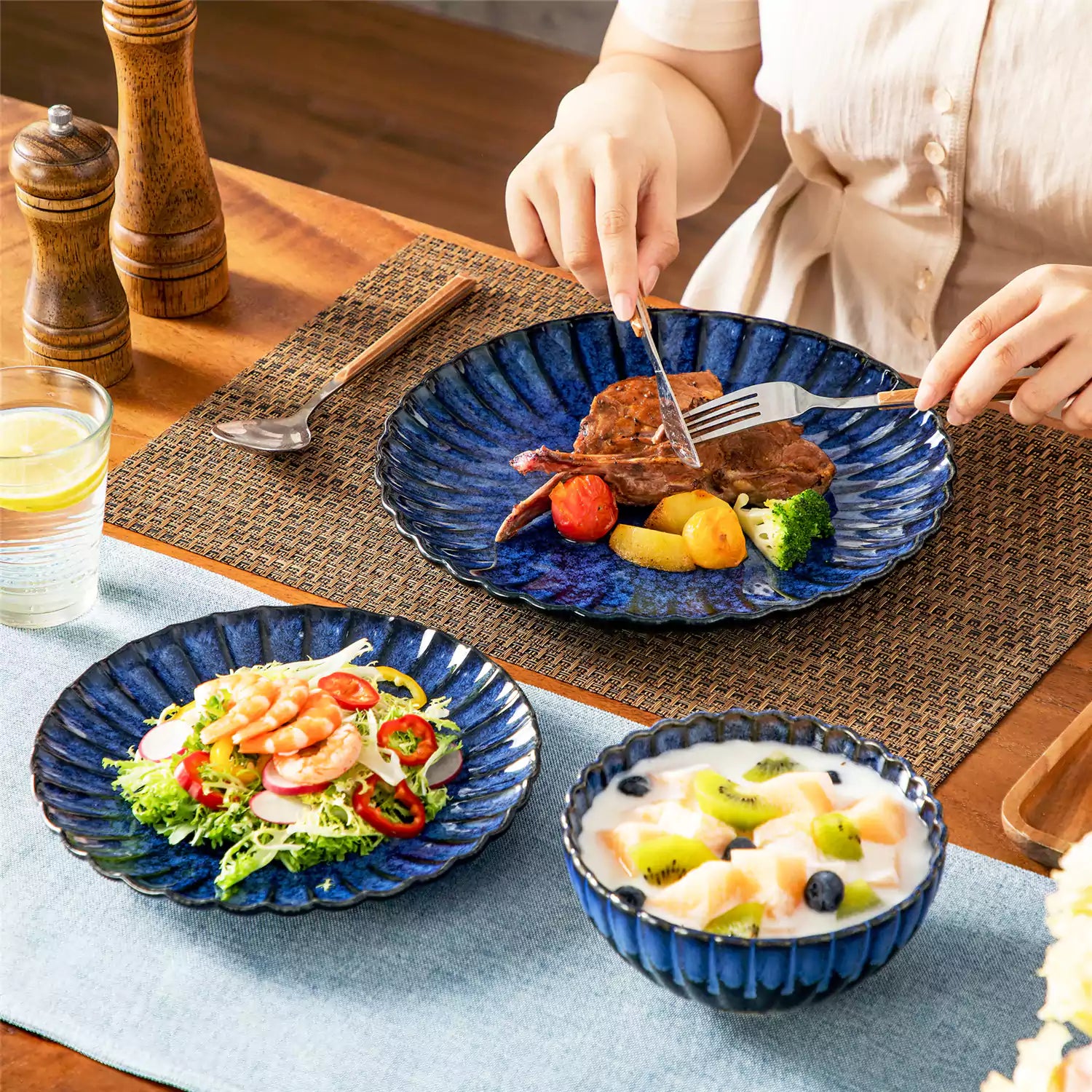 Blue reactive glaze stoneware bowls and plates from the Adonis 12 piece set with brown placemats and fresh flowers