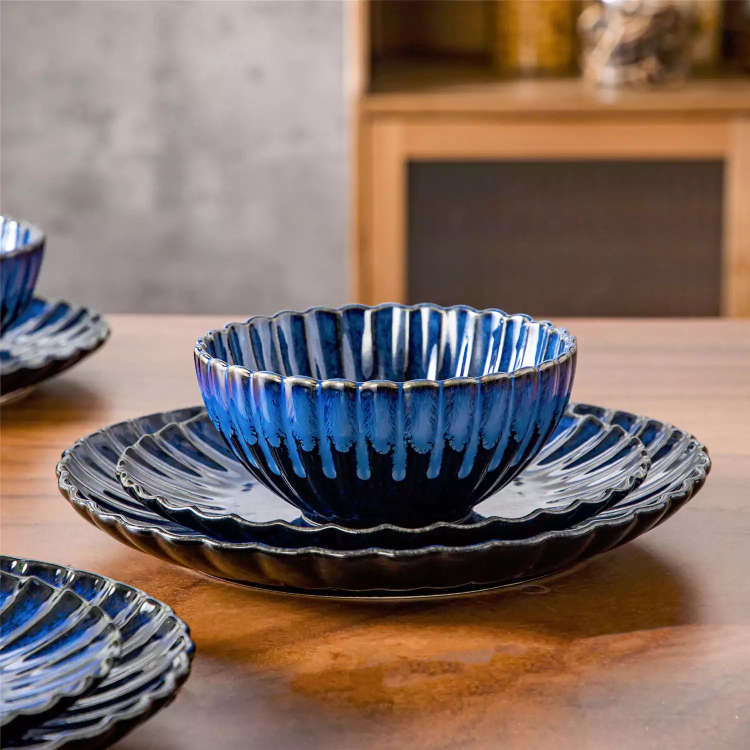 Adonis 18 piece reactive glaze dinnerware set in deep blue with ribbed bowls and plates on a dining table