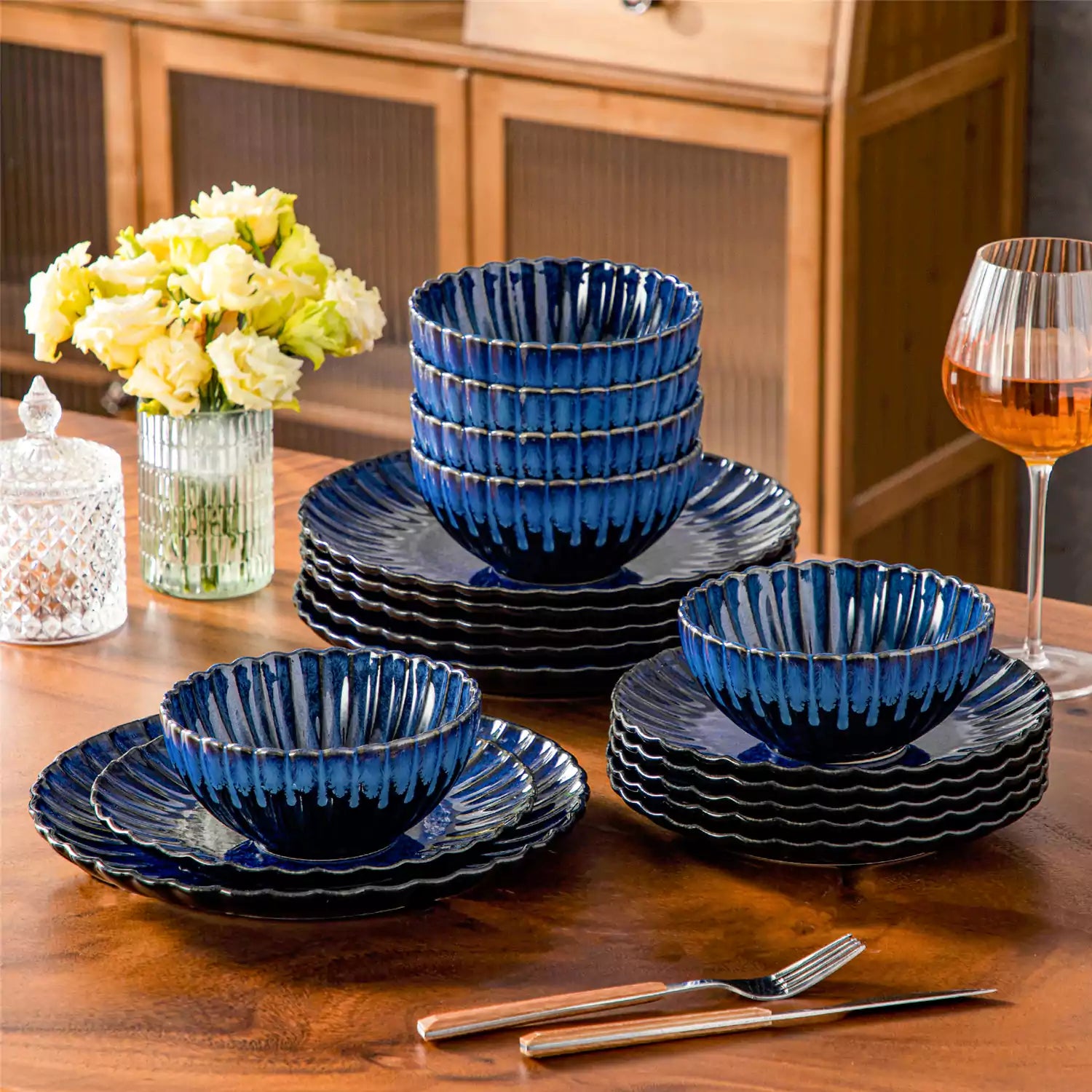 Adonis 18 piece reactive glaze dinnerware set in deep blue with ribbed bowls and plates on a dining table