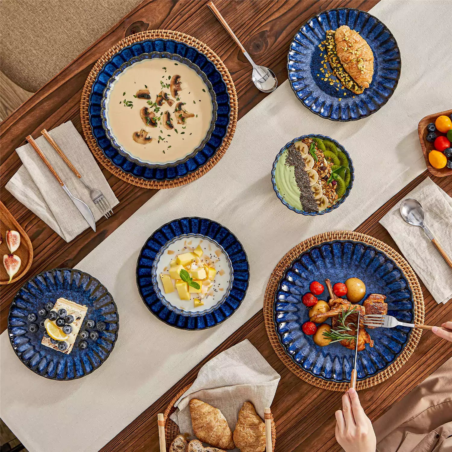 Adonis 16 piece reactive glaze dinnerware set in teal blue with pasta steak and fruit on a wooden dining table