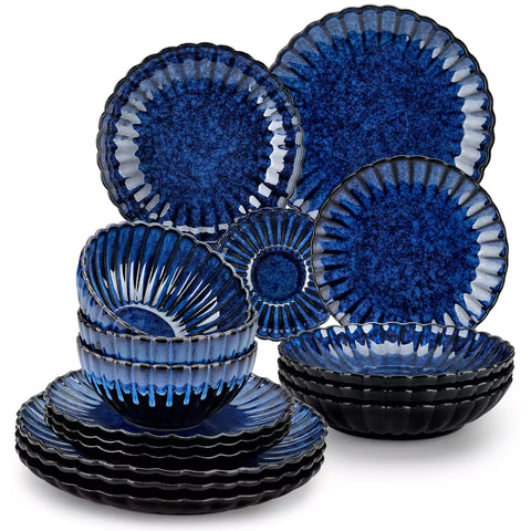 Adonis 16 piece reactive glaze dinnerware set in teal blue with pasta steak and fruit on a wooden dining table