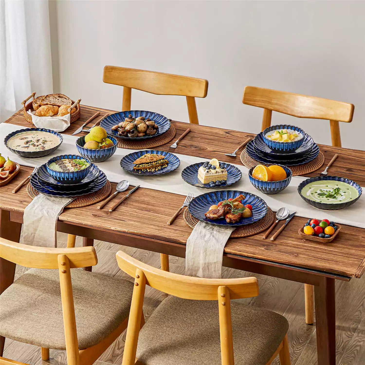 Adonis 16 piece reactive glaze dinnerware set in teal blue with pasta steak and fruit on a wooden dining table