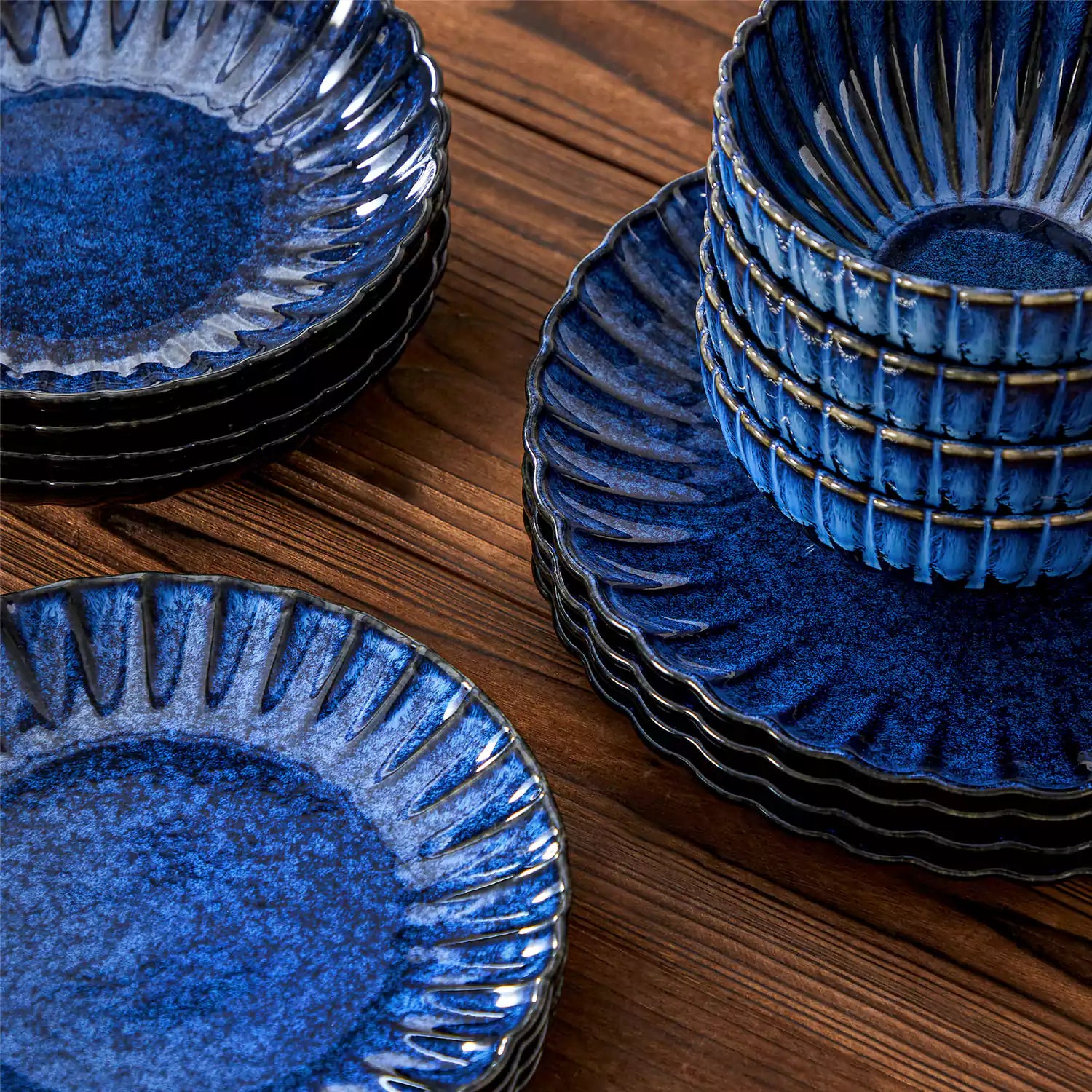 Adonis 16 piece reactive glaze dinnerware set in teal blue with pasta steak and fruit on a wooden dining table