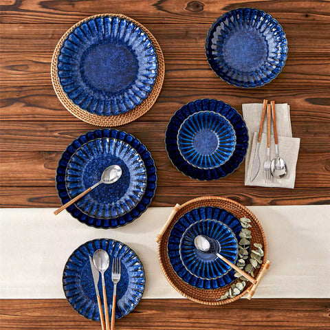 Adonis 16 piece reactive glaze dinnerware set in teal blue with pasta steak and fruit on a wooden dining table