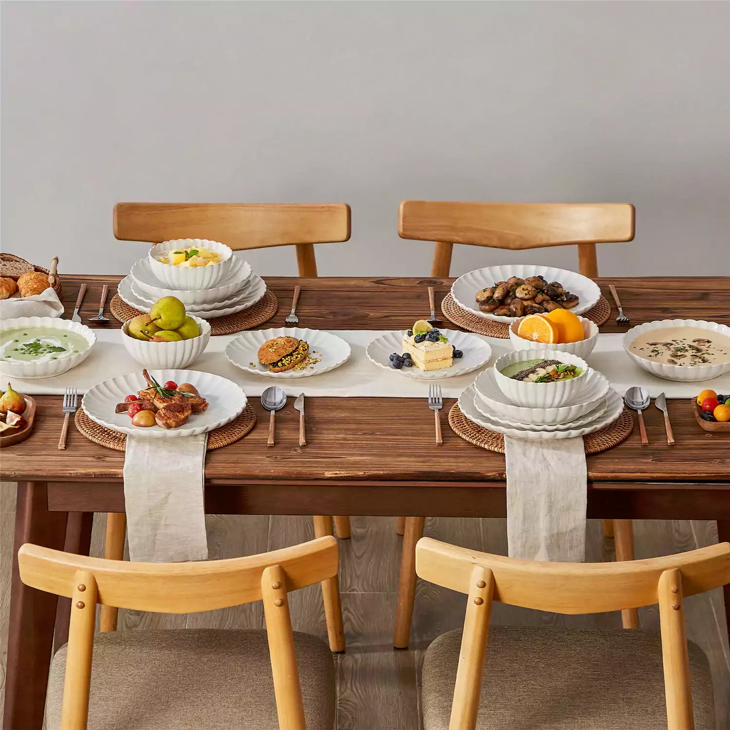 Adonis 16 piece reactive glaze dinnerware set in beige with pasta steak and fruit on a wooden dining table