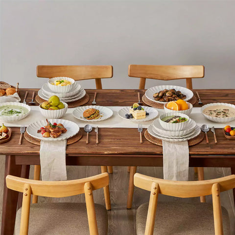 Adonis 16 piece reactive glaze dinnerware set in beige with pasta steak and fruit on a wooden dining table