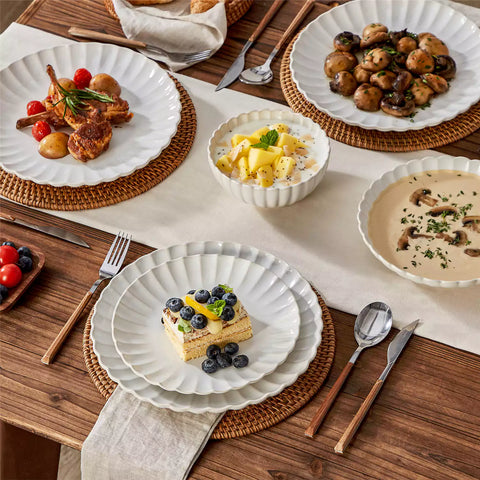 Adonis 16 piece reactive glaze dinnerware set in beige with pasta steak and fruit on a wooden dining table