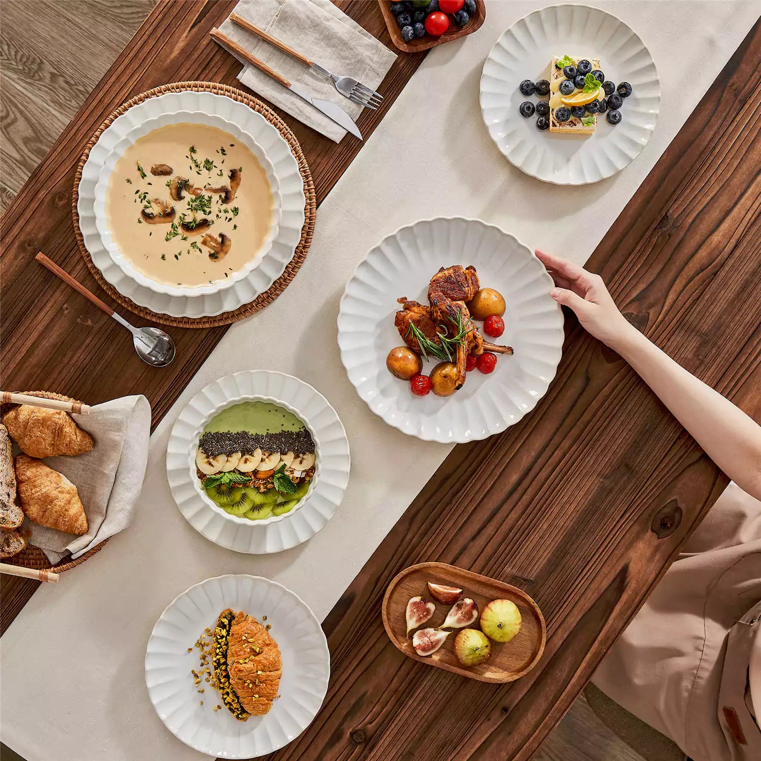 Adonis 16 piece reactive glaze dinnerware set in beige with pasta steak and fruit on a wooden dining table
