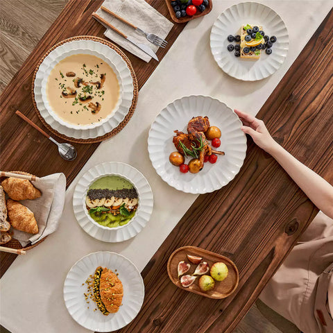 Adonis 16 piece reactive glaze dinnerware set in beige with pasta steak and fruit on a wooden dining table