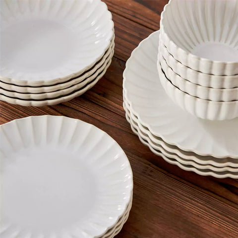 Adonis 16 piece reactive glaze dinnerware set in beige with pasta steak and fruit on a wooden dining table