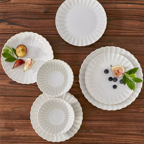 Adonis 16 piece reactive glaze dinnerware set in beige with pasta steak and fruit on a wooden dining table