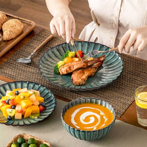 Green reactive glaze stoneware bowls and plates from the Adonis 12 piece set with brown placemats and fresh flowers