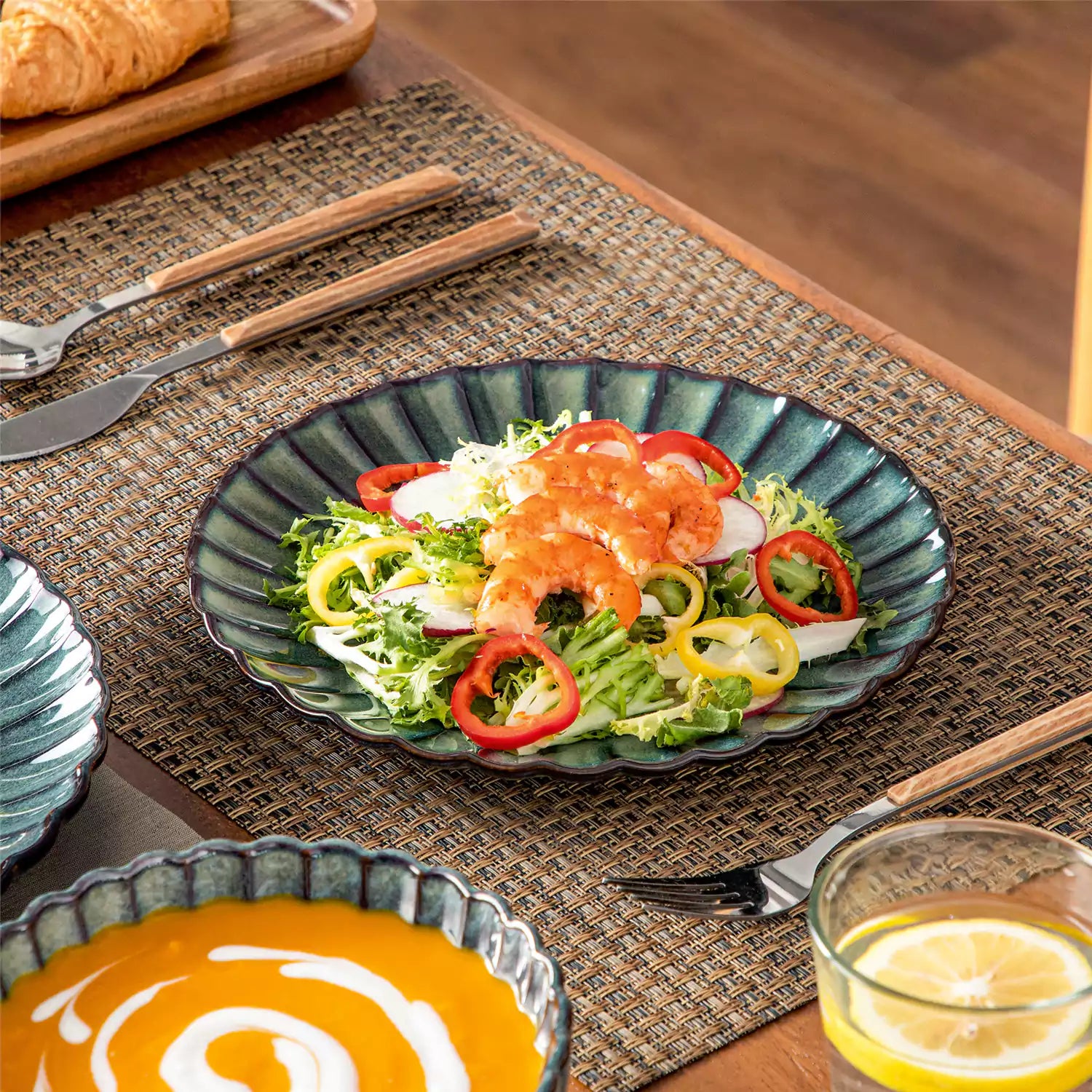 Adonis 18 piece reactive glaze dinnerware set in teal green with ribbed bowls and plates on a dining table