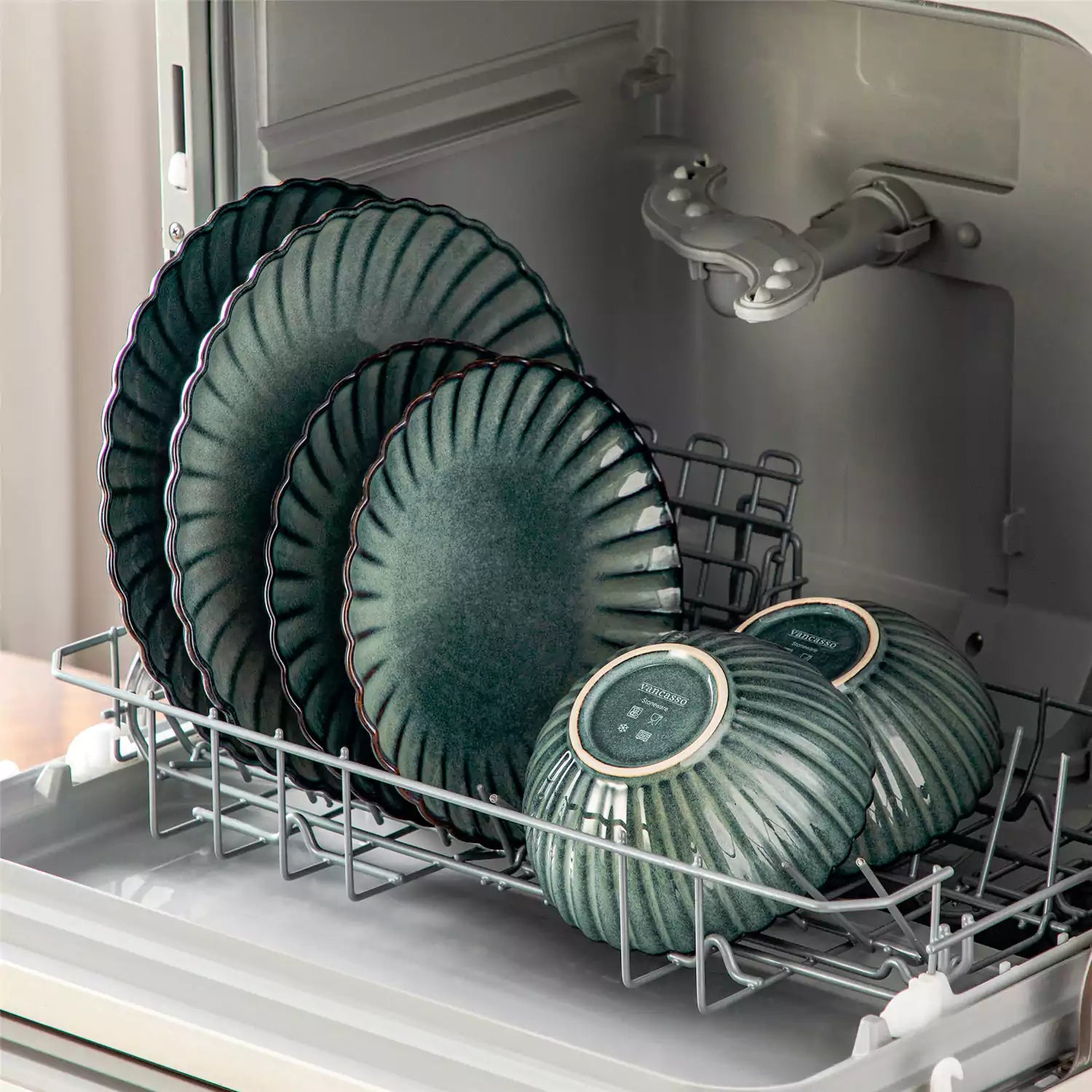 Adonis 18 piece reactive glaze dinnerware set in teal green with ribbed bowls and plates on a dining table