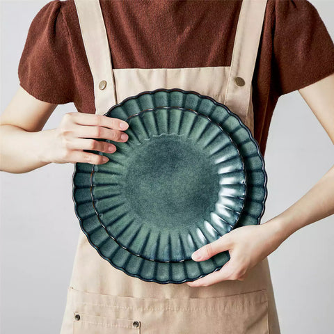 Adonis 16 piece reactive glaze dinnerware set in teal green with pasta steak and fruit on a wooden dining table