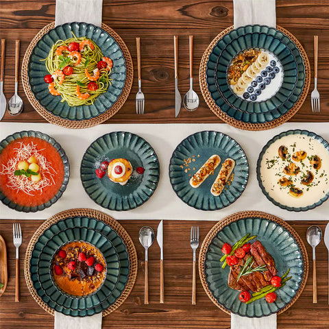 Adonis 16 piece reactive glaze dinnerware set in teal green with pasta steak and fruit on a wooden dining table