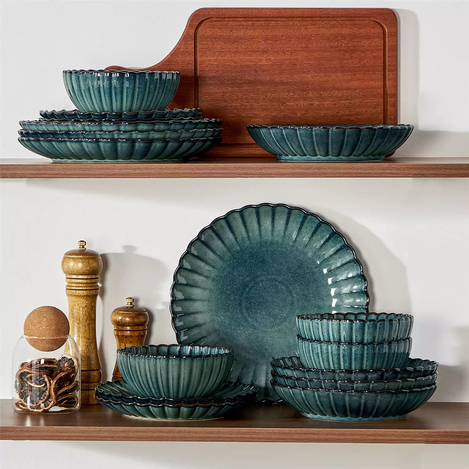 Adonis 16 piece reactive glaze dinnerware set in teal green with pasta steak and fruit on a wooden dining table