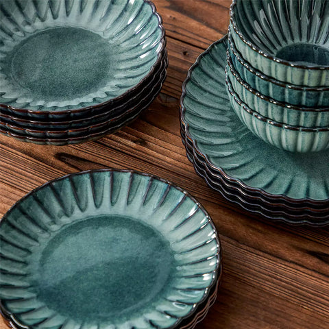 Adonis 16 piece reactive glaze dinnerware set in teal green with pasta steak and fruit on a wooden dining table