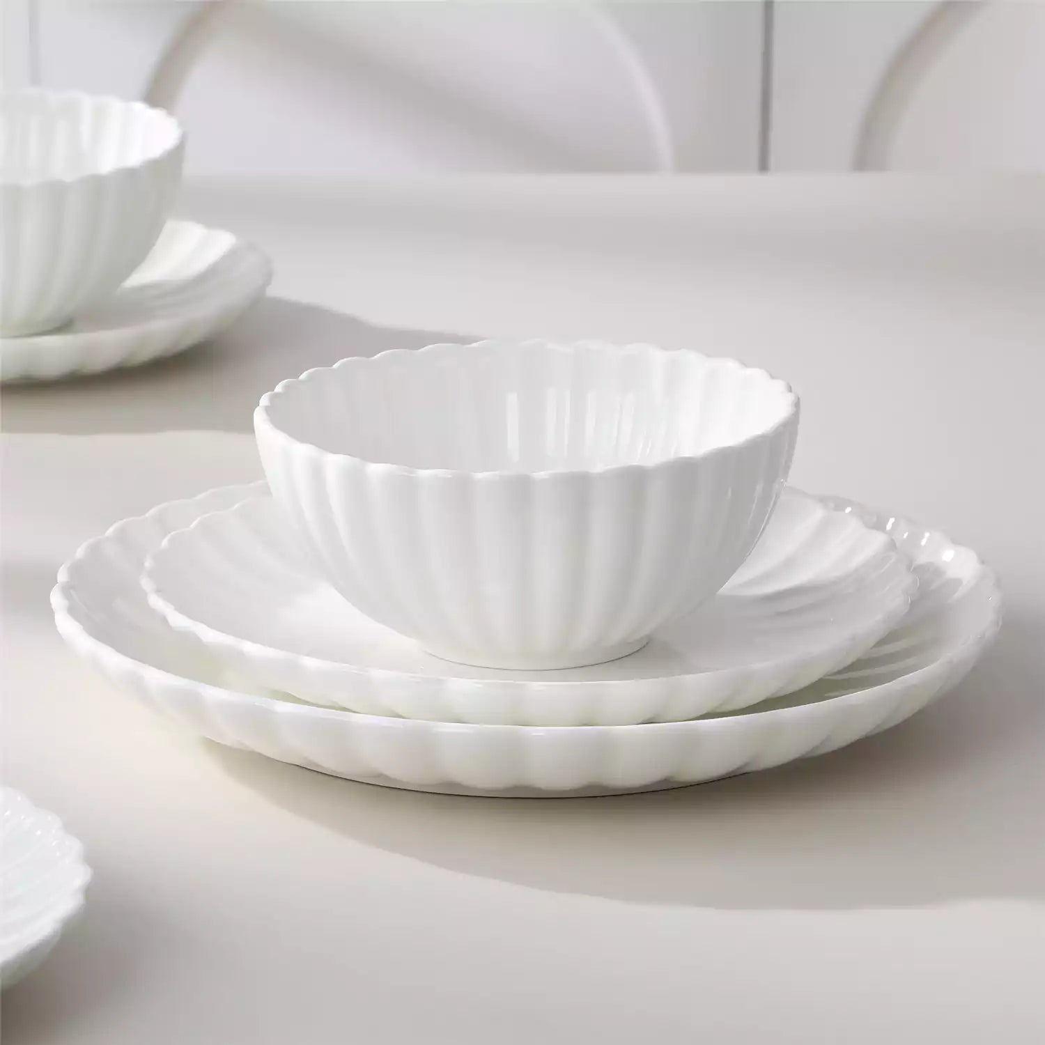 Bright modern dining room with Adonis white porcelain plates bowls white chairs and light wood accents