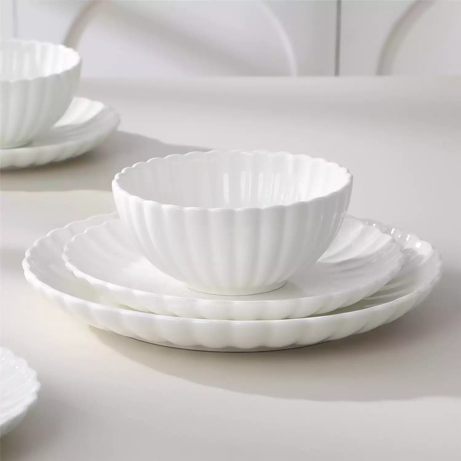 Adonis 18 piece white porcelain dinnerware set styled with food and glassware on a modern dining table