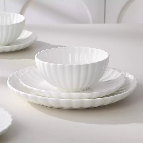 Adonis 18 piece white porcelain dinnerware set styled with food and glassware on a modern dining table