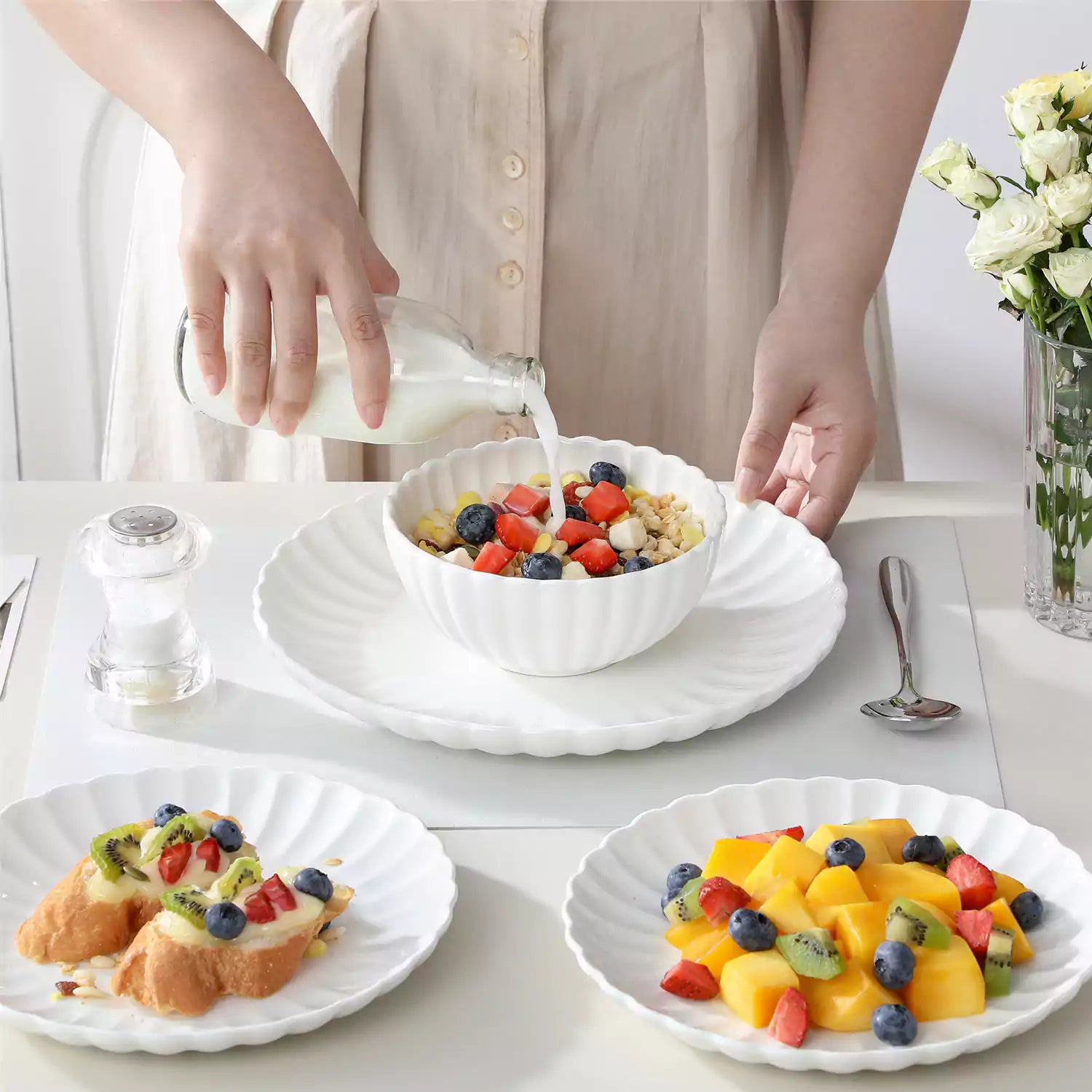 Adonis 18 piece white porcelain dinnerware set styled with food and glassware on a modern dining table