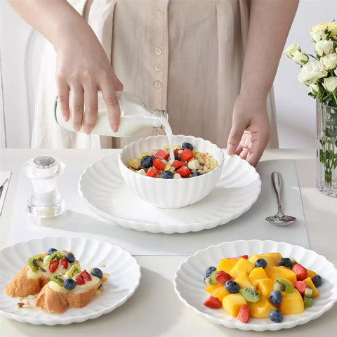 Adonis 18 piece white porcelain dinnerware set styled with food and glassware on a modern dining table