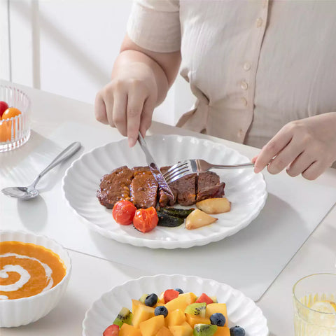 Adonis 18 piece white porcelain dinnerware set styled with food and glassware on a modern dining table