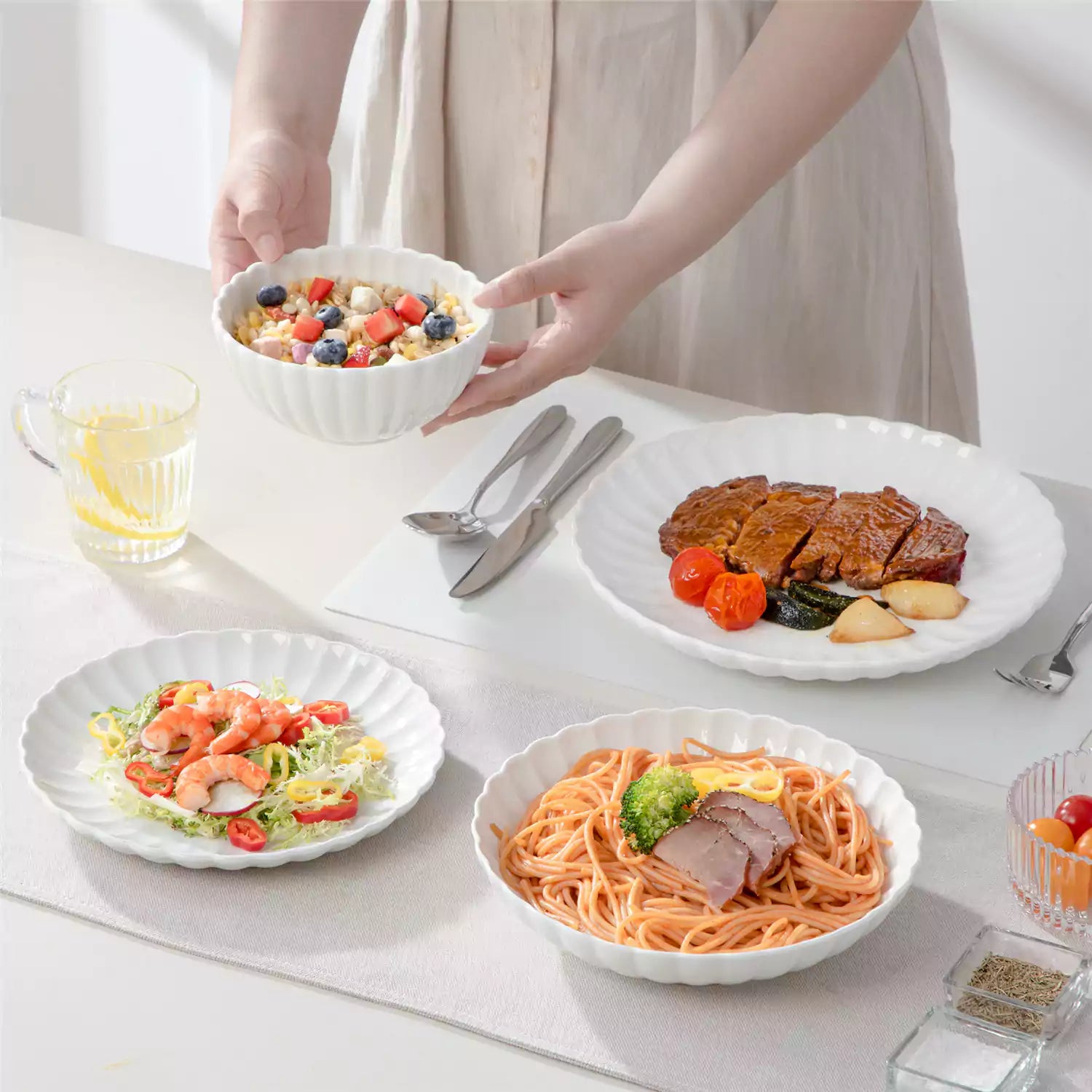 Adonis 24 piece white porcelain dinnerware set for 6 styled with pasta soup and fruit on a modern dining table