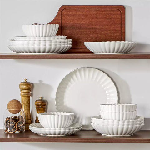 Adonis 16 piece white porcelain dinnerware set with steak pasta and fruit on a wooden dining table