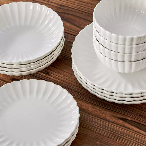 Adonis 16 piece white porcelain dinnerware set with steak pasta and fruit on a wooden dining table